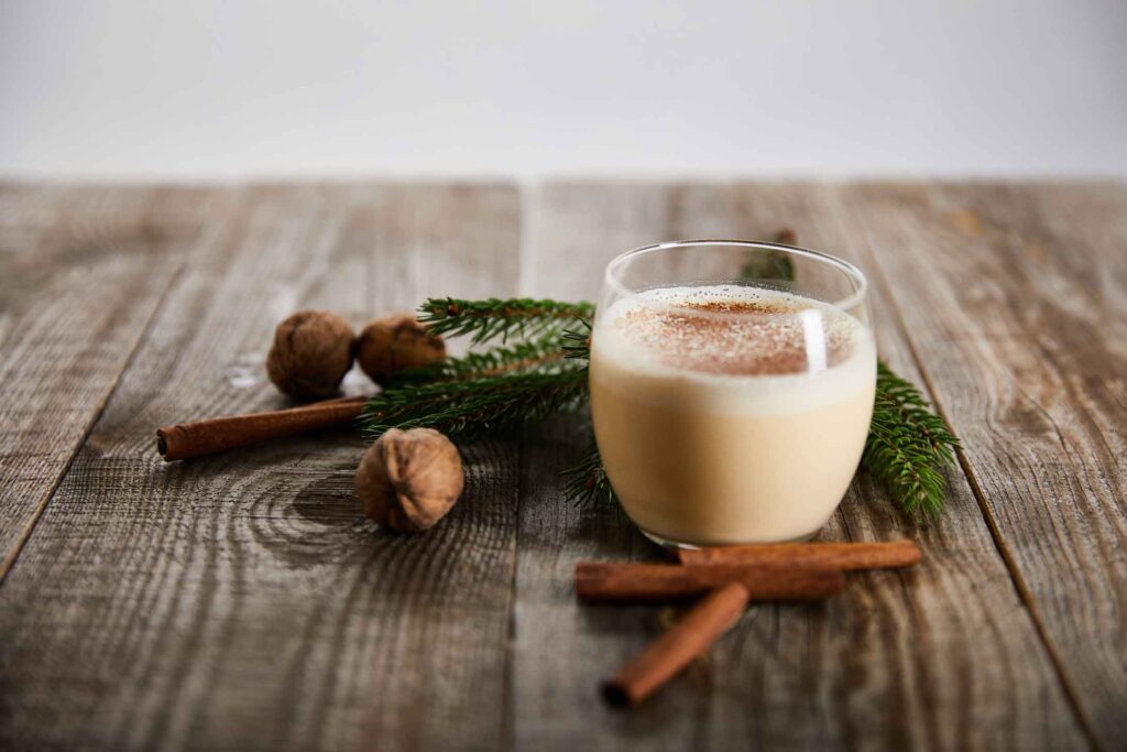 glass of eggnog on a board with cinnamon sticks