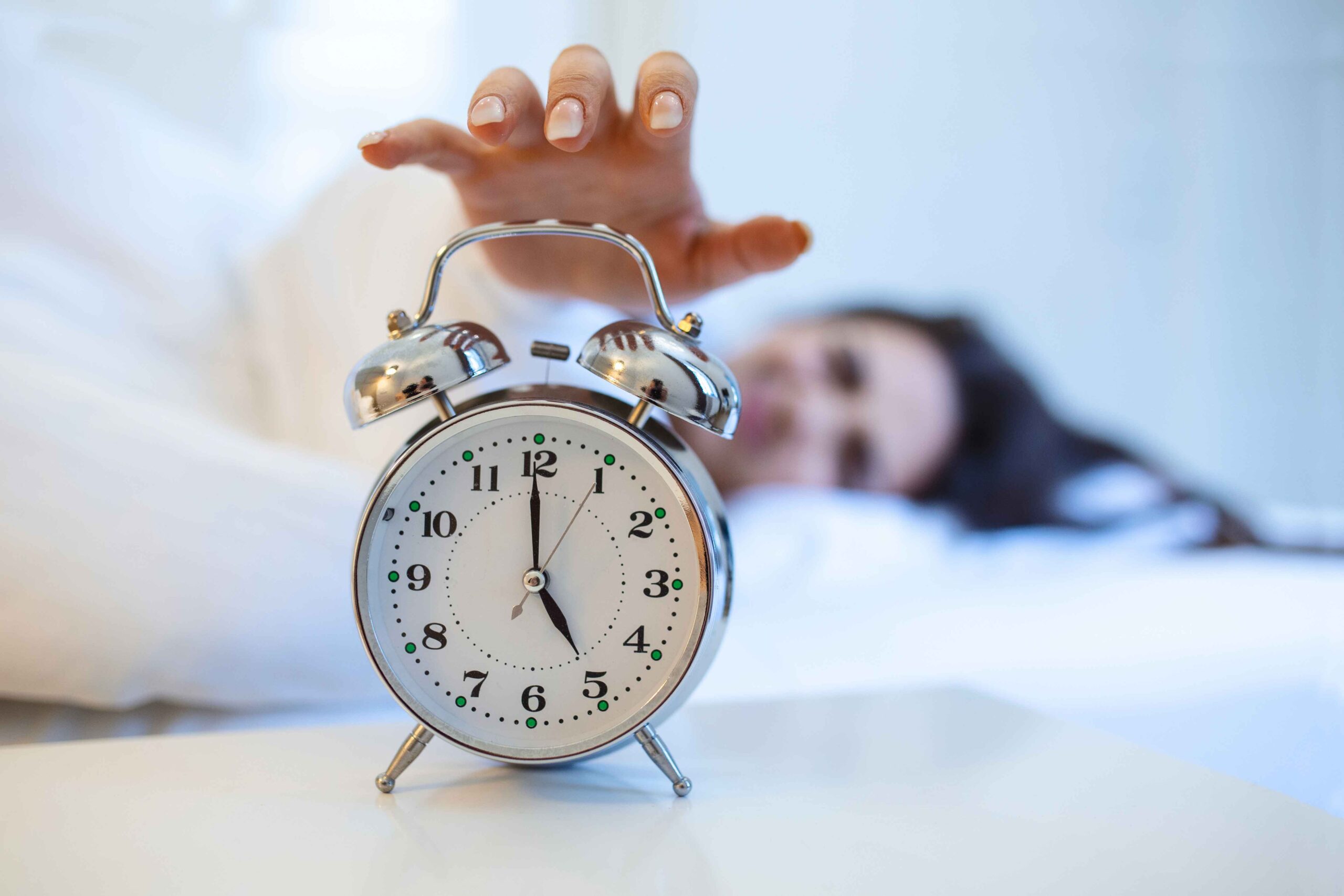 woman about to hit an alarm clock set for 5am