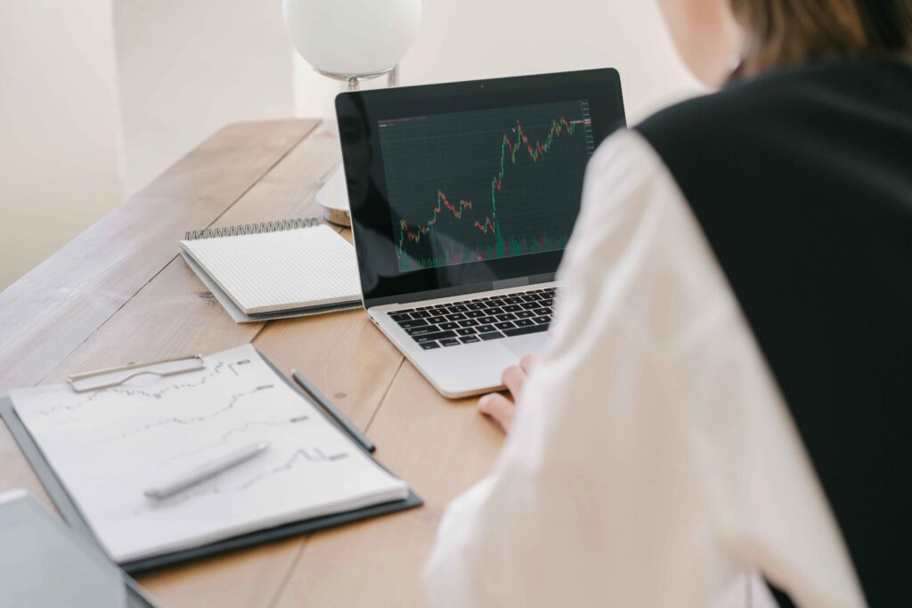 the back of a person looking at a laptop with a chart at a desk