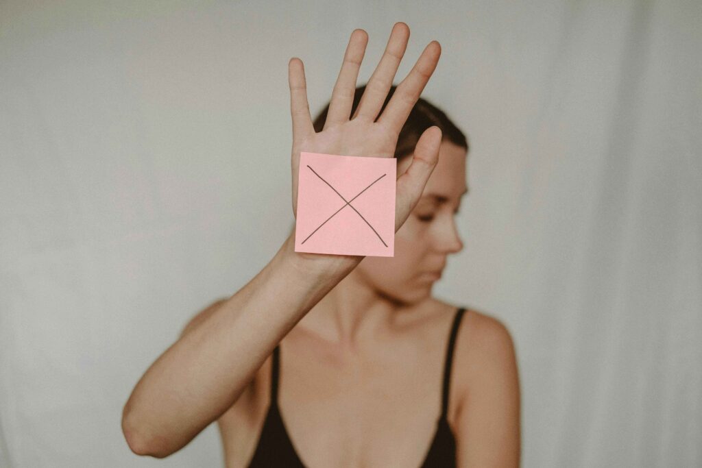 a woman with her hand up with a stickie note with an "x" on it.  