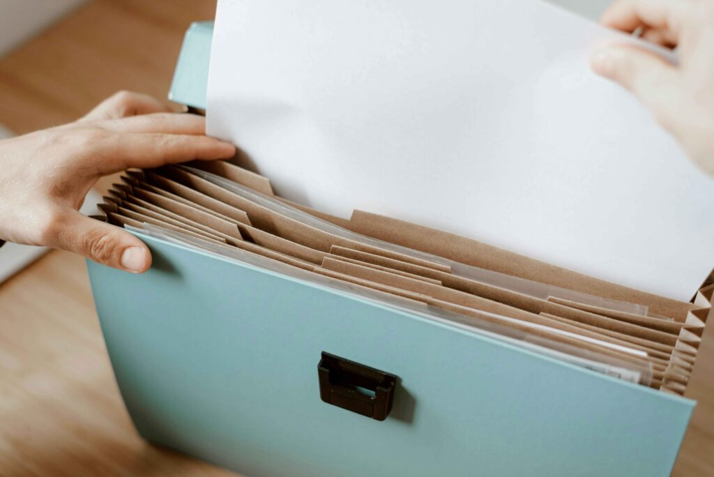 teal acordian file folder with a person's hand holding it.  thrive in business