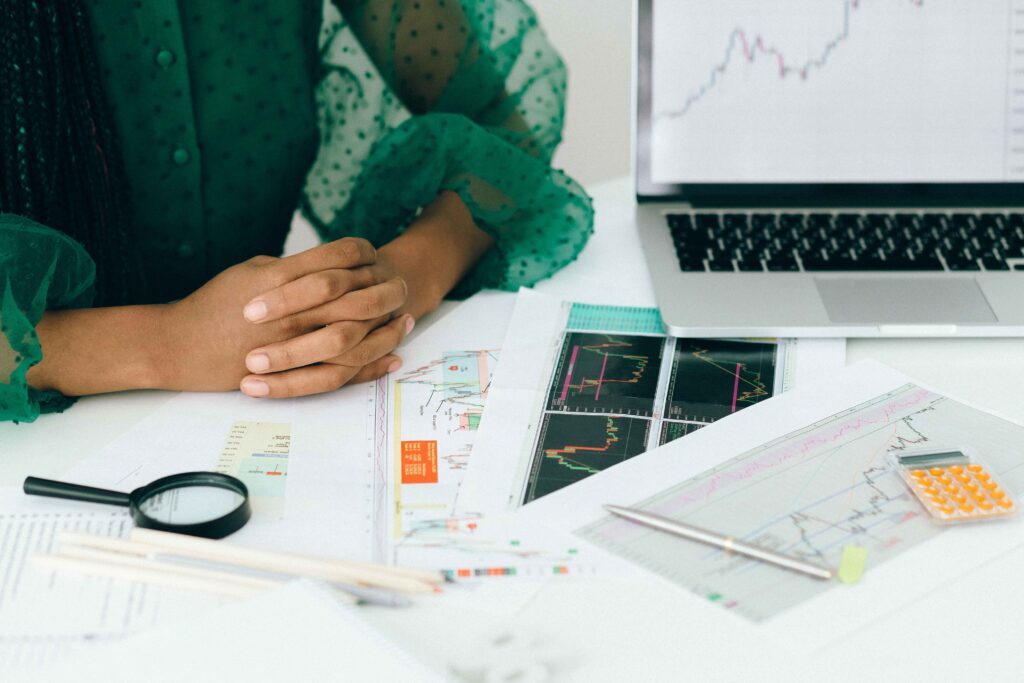 woman in front of a laptob with spreadsheets printed in front of her