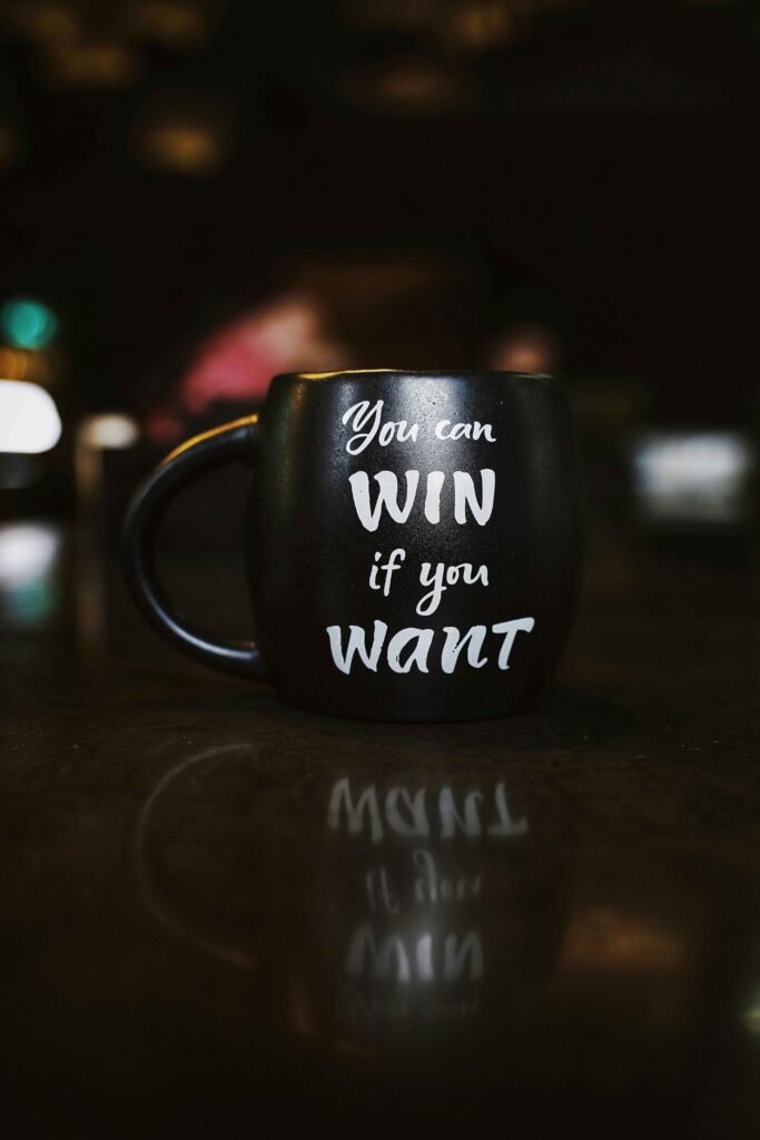 black coffee mug on a table with the words - you can win if you want.  entprepreneur mindset