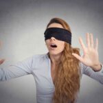 woman blindfolded with her hands up - it shows someone facing the fear of the unkown. Overcome the Fear of Leaving Your 9-to-5