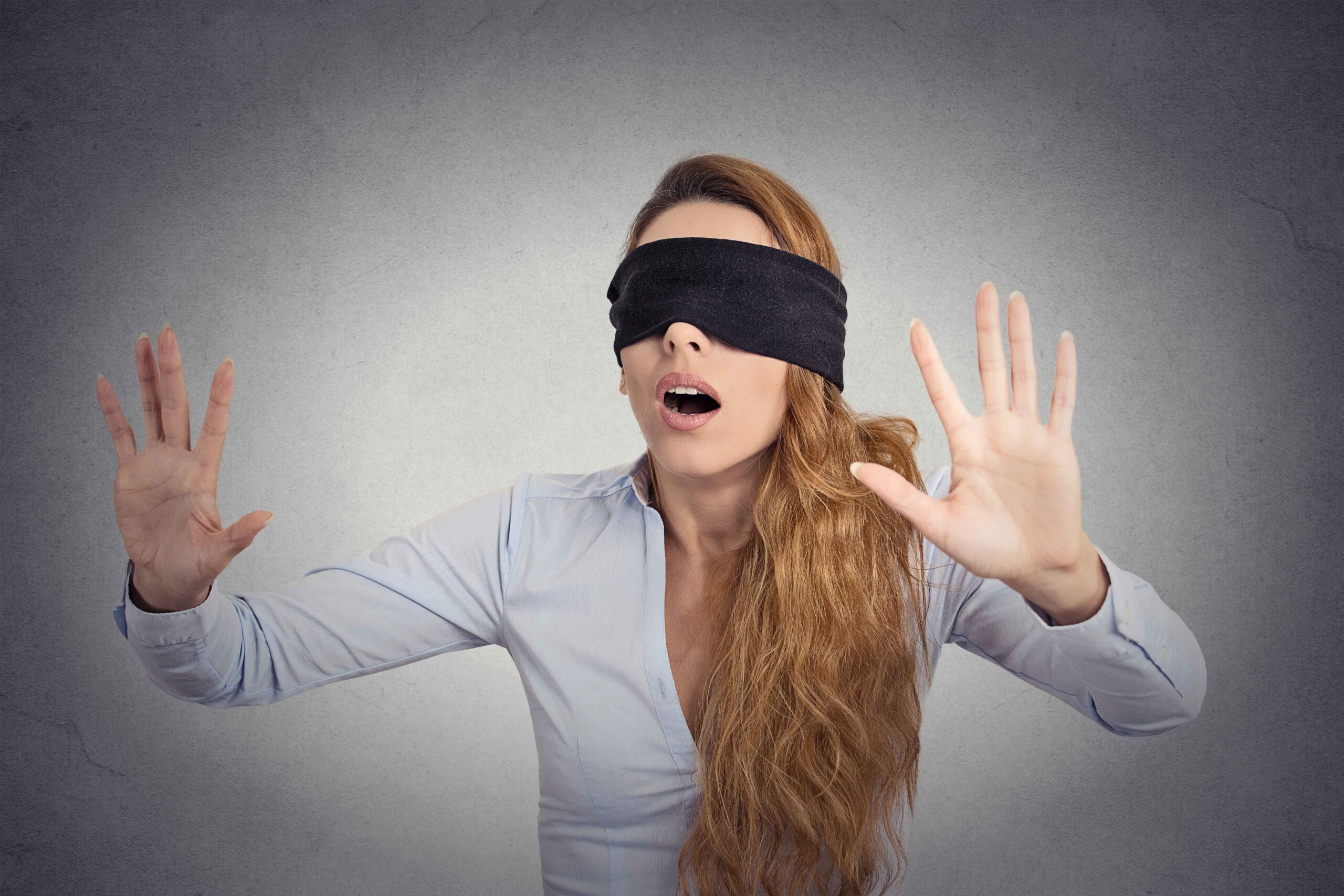 woman blindfolded with her hands up - it shows someone facing the fear of the unkown. Overcome the Fear of Leaving Your 9-to-5